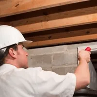 Termite inspection technician checking a basement wall and framing for termite activity in Kansas City, MO